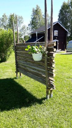 a potted planter made out of wooden sticks on the grass in front of a house