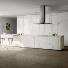 a modern kitchen with marble counter tops and white cabinets, along with bar stools