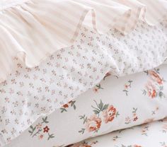 three pillows stacked on top of each other with pink and white floral print, one has ruffled edges