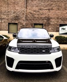 the front end of a white range rover parked in a parking lot next to a brick building