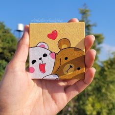 a hand holding up a small box with two bears on it