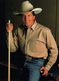 a man in a cowboy hat holding a pool stick