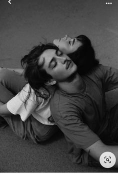 a man and woman laying on the ground with their heads close to each other's eyes