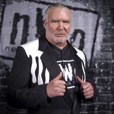 an older man in a black and white jacket posing for the camera with his hand on his hip