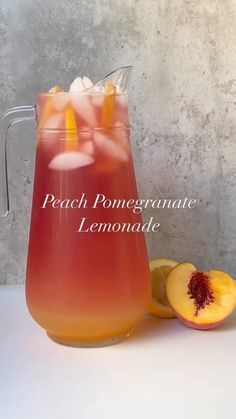 peach pomegranate lemonade in a pitcher next to sliced peaches