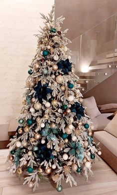 a white christmas tree with blue and gold ornaments on it's branches in a living room