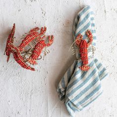 two napkins with lobster pins on them are sitting next to each other in front of a white wall