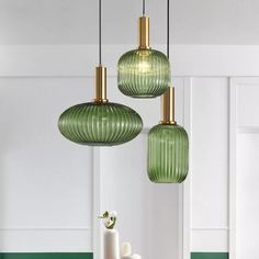 three green glass pendant lights hanging over a dining room table