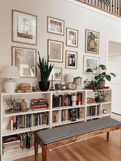 a bookshelf filled with lots of books next to a stair case covered in pictures