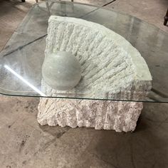 a glass and stone table with a ball on the top, in a living room