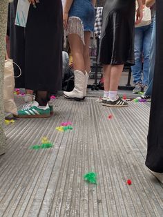 several people are standing on the sidewalk with their feet in the air and colorful confetti all around them