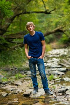 a young man standing in the middle of a stream