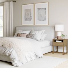 a white bed sitting in a bedroom next to two framed pictures