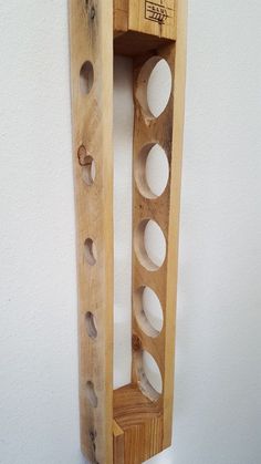 a wooden shelf with several holes in the bottom and one hole at the top that is filled with eggs