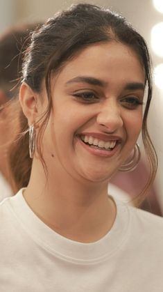 a woman smiling and looking at the camera while wearing large hoop earrings on her head