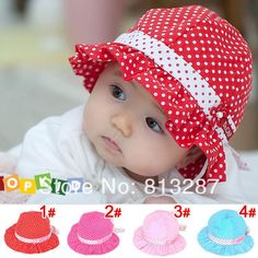 a baby wearing a red and white hat with polka dots on the front, four different colors