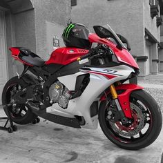 a red and white motorcycle parked in front of a building