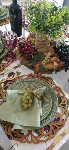 the table is set with grapes, wine and other items for an elegant dinner party