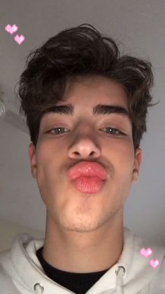 a young man making a funny face with pink hearts on the wall behind his head