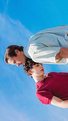 two men standing next to each other in front of a blue sky