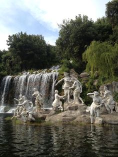 the statues are in front of a waterfall