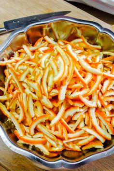 a metal bowl filled with sliced carrots on top of a wooden table