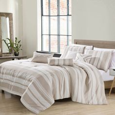 a bed in a bedroom with white walls and wooden flooring next to a large window