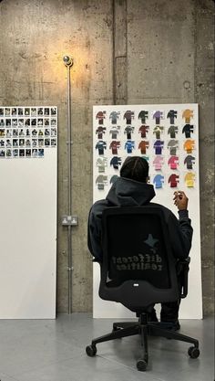 a person sitting in an office chair looking at a wall with pictures on it