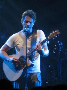 a man holding a guitar and singing into a microphone