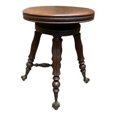 an antique wooden stool with turned legs and foot rests against a white background for display