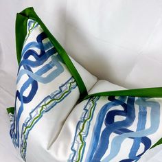 a white pillow with blue and green designs on the front, sitting on a white surface