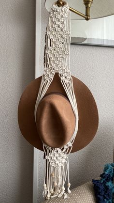 a hat hanging from a hook on a wall with a mirror in the back ground