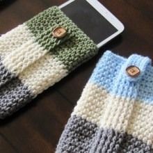 two crocheted sweaters sitting on top of a wooden table next to an ipad