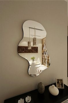 a mirror that is on the side of a wall next to a table and vase