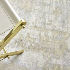 an upholstered white and gold chair on a beige rug with a golden metal leg rest