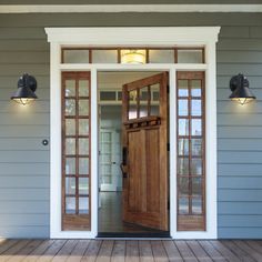 an open front door on a house with two lights above the doors and wood flooring