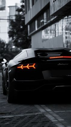 a black sports car parked in front of a tall building