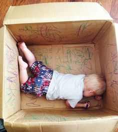 a baby in a cardboard box with writing on it