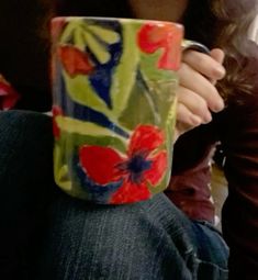 a close up of a person holding a coffee cup with flowers on it's side