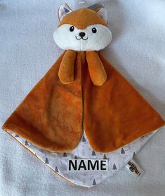 a stuffed animal with a name tag on it's neck and an orange scarf around its neck