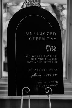 a black and white photo of an unplugged ceremony sign in front of a window