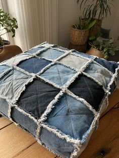 a blue and white cushion sitting on top of a wooden table next to a potted plant