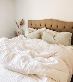 an unmade bed with white sheets and pillows