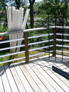 an umbrella stand on a wooden deck with white railings and trees in the background