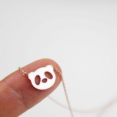 a person's finger with a tiny necklace that has a small panda face on it