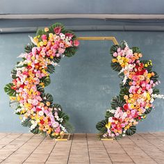 two wreaths made out of fake flowers are on the floor in front of a blue wall
