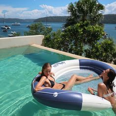 two women are sitting in an inflatable pool on the edge of a swimming pool