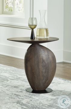 two wine glasses sitting on top of a wooden table next to a vase and glass