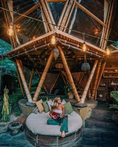 a woman sitting on top of a round couch in front of a wooden structure with lights