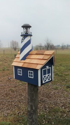 a blue and white lighthouse on top of a wooden post